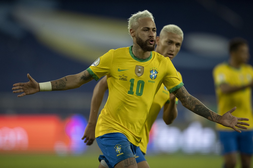 De braços abertos, Neymar comemora gol vestido com a camisa amarela e o shortts azul da seleção brasileira