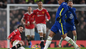 Sob olhares de Cristiano Ronaldo, ao fundo, Bruno Fernandes, do United, tenta tomar com um carrinho a bola de Thiago Silva, do Chelsea