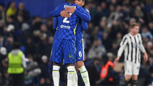 Thiago Silva, de frente para a câmara e de costas para a torcida, abraça o companheiro Rudiger (Chelsea está de camisa e shorts azuis e meião branco)