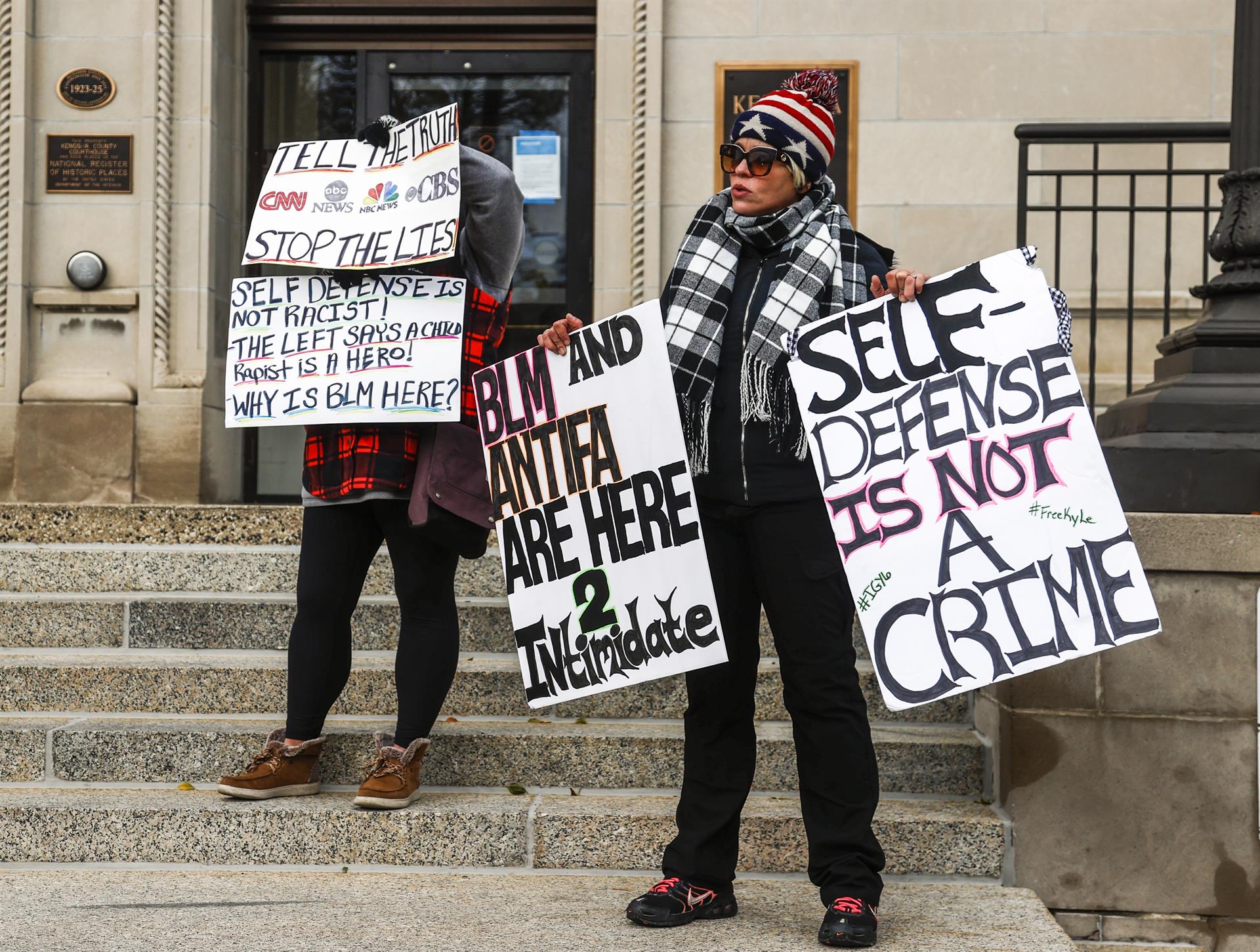 pessoas com placa 'legítima defesa não é crime' diante da corte em Wisconsin