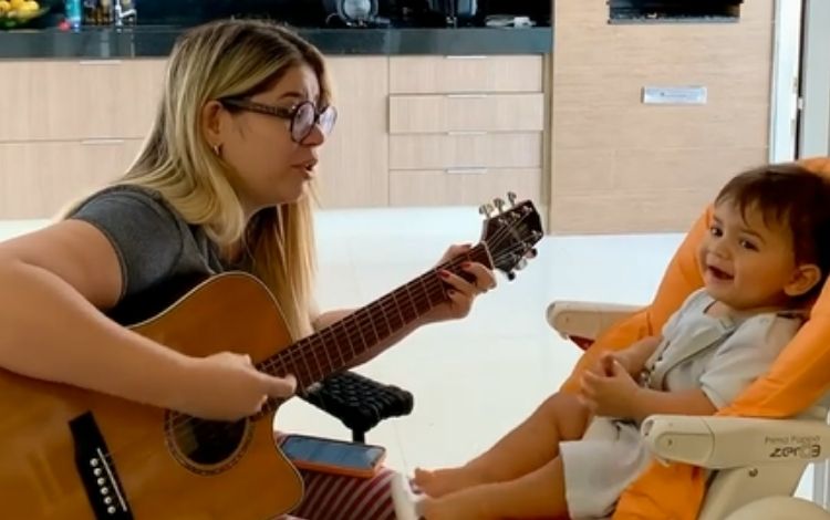 Marília Mendonça tocando violão para o filho
