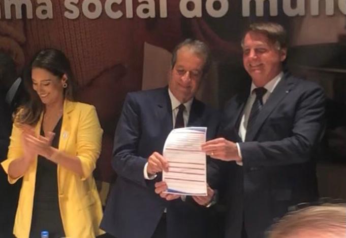 O presidente Jair Bolsonaro ao lado de Valdemar da Costa, presidente do PL, segurando o papel que firma a sua filiação à legenda