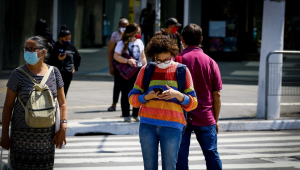 Pessoas usando máscara e atravessando a faixa de pedestre em São Paulo