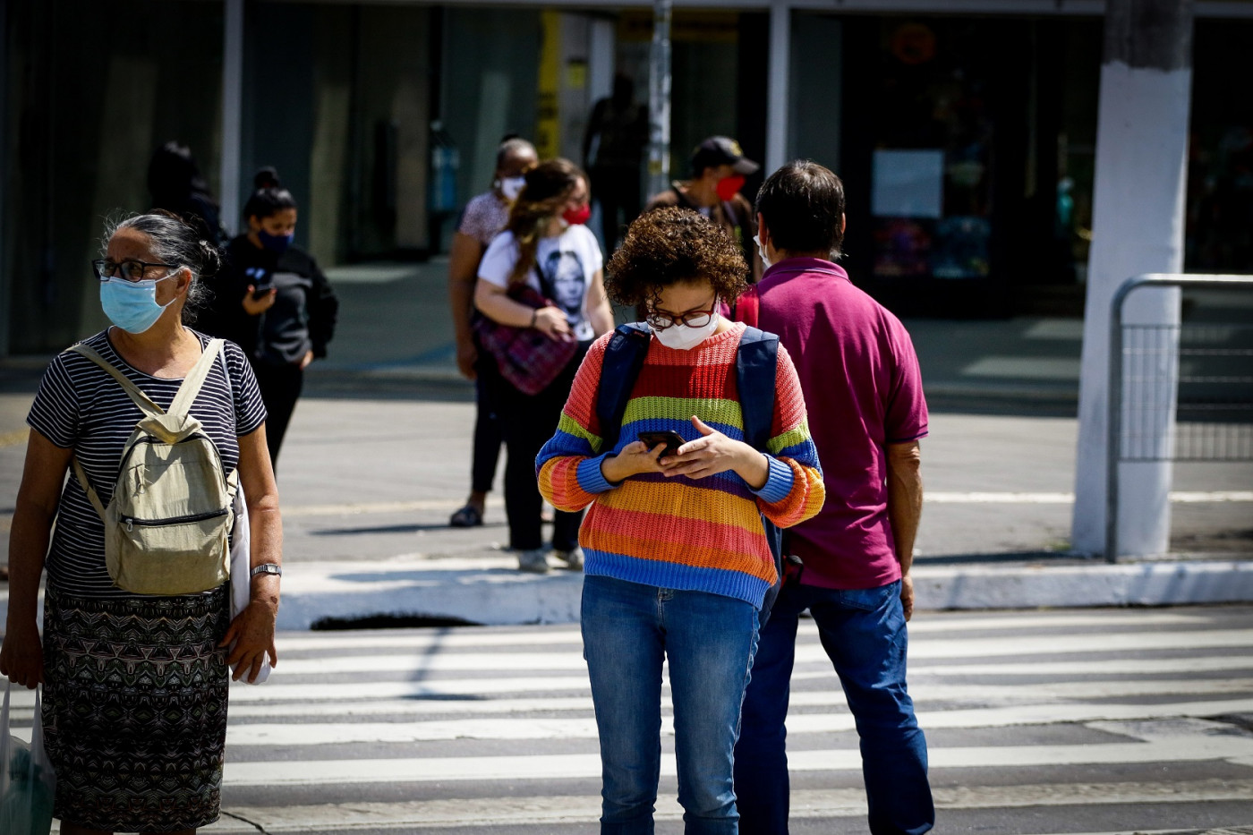 Pessoas usando máscara e atravessando a faixa de pedestre em São Paulo