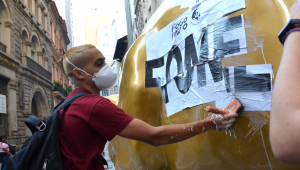 Protesto de grupos sociais em frente a Bolsa de São Paulo, (B3) na manhã desta quarta feira, (17). Na foto manifestantes colam cartaz escrito fome na escultura do Touro de Ouro