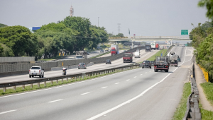 Rodovia Dutra livre nos dois sentidos, com foco na pista que aparece à direita na imagem, na qual transitam dois caminhões e três carros