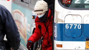 Mulher desce de ônibus usando máscara