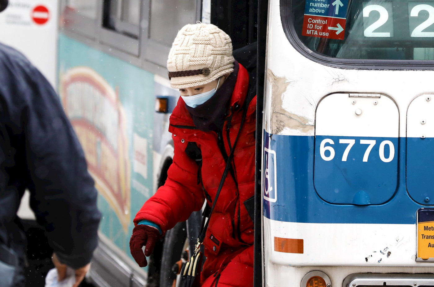 Mulher desce de ônibus usando máscara