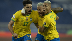Paquetá, Neumar e Rocharlison correm abraçados, com cara de satisfação, comemorando gol da seleção brasileira; eles usam camisa amarela e calção azul