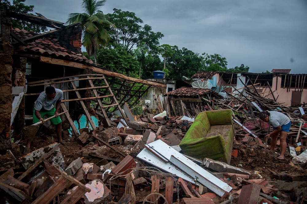 Pessoas tentam resgatar seus pertences em casas destruídas pelas enchentes provocadas pelas chuvas, na cidade de Itambé, no estado da Bahia