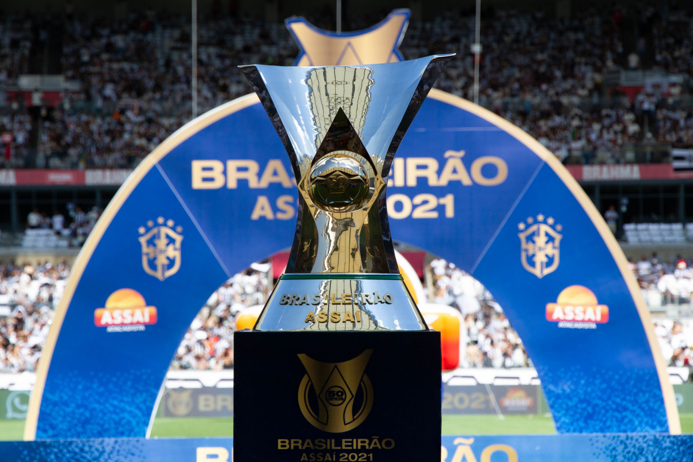 Taça do Brasileirão colocada em pedestal em frente a arco com o nome do campeonato