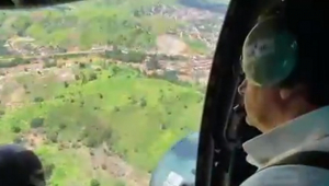 Homem com fone de ouvido olha através de porta aberta de helicóptero