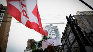 Na entrada do restaurante Rybayat, onde ocorreu encontro entre Lula e Alckmin, mão segura cartaz de "Alckmin não" perto de onde est[a estendida bandeira do PT