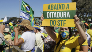 Durante uma lotada manifestação pró-Bolsonaro em Brasília, mulher exibe cartaz verde e amarelo com a mensagem "abaixo a ditadura do STF"