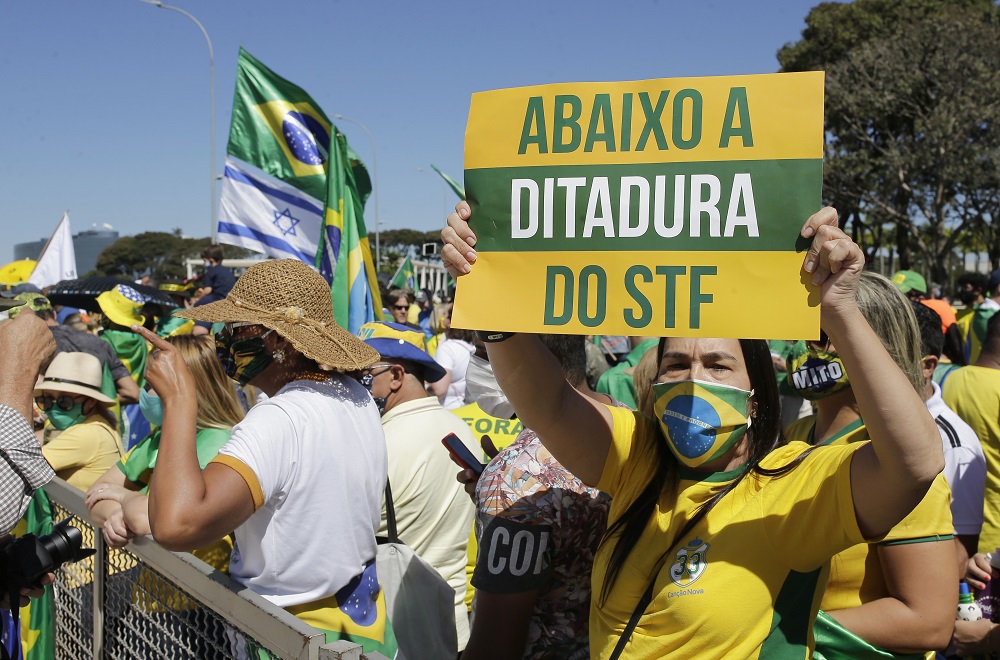 Durante uma lotada manifestação pró-Bolsonaro em Brasília, mulher exibe cartaz verde e amarelo com a mensagem 