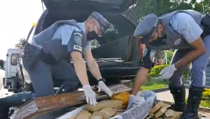 Dois policiais abem caixão que carregava tabletes de maconha
