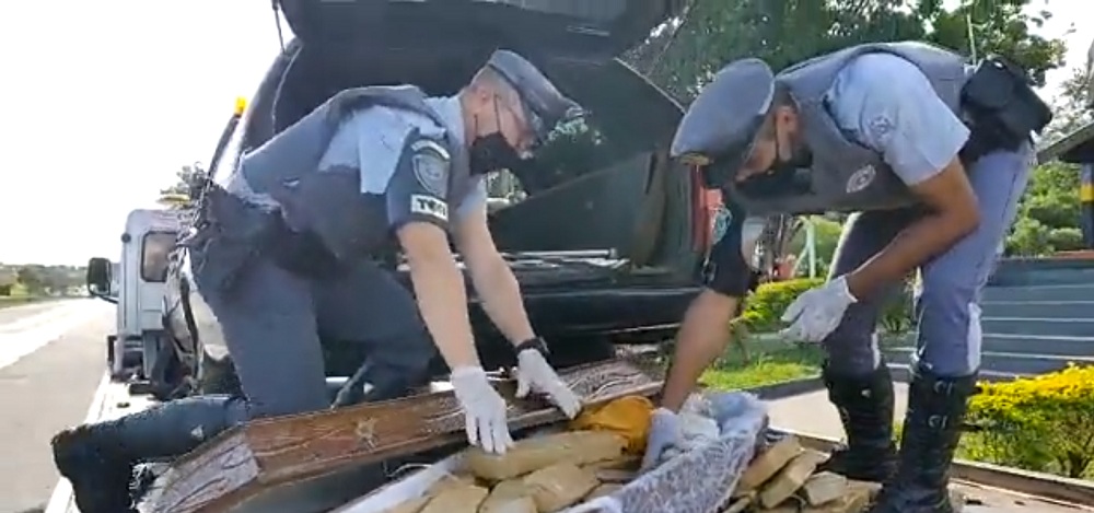 Dois policiais abem caixão que carregava tabletes de maconha