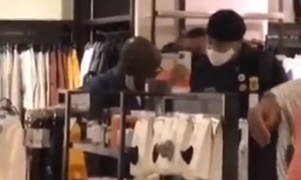 Home negro conversa com segurança em loja de roupas