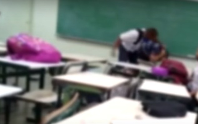 Dois homens se agridem em sala de aula com carteiras e mochilas espalhadas