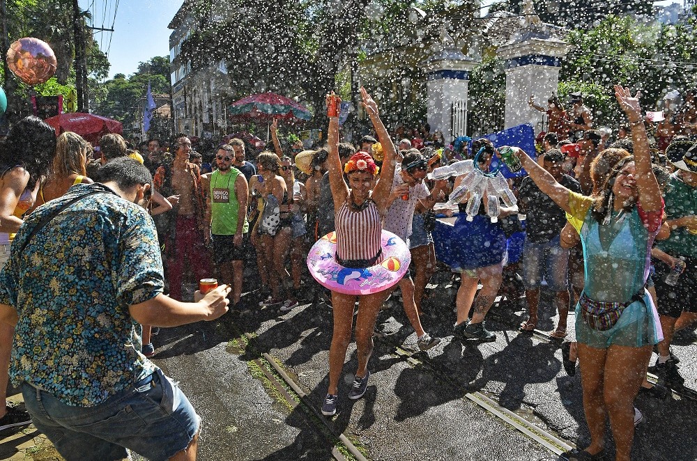 Foliões são borrifados com água em uma festa de rua durante o bloco anual 'Ceu Na Terra', no Rio de Janeiro