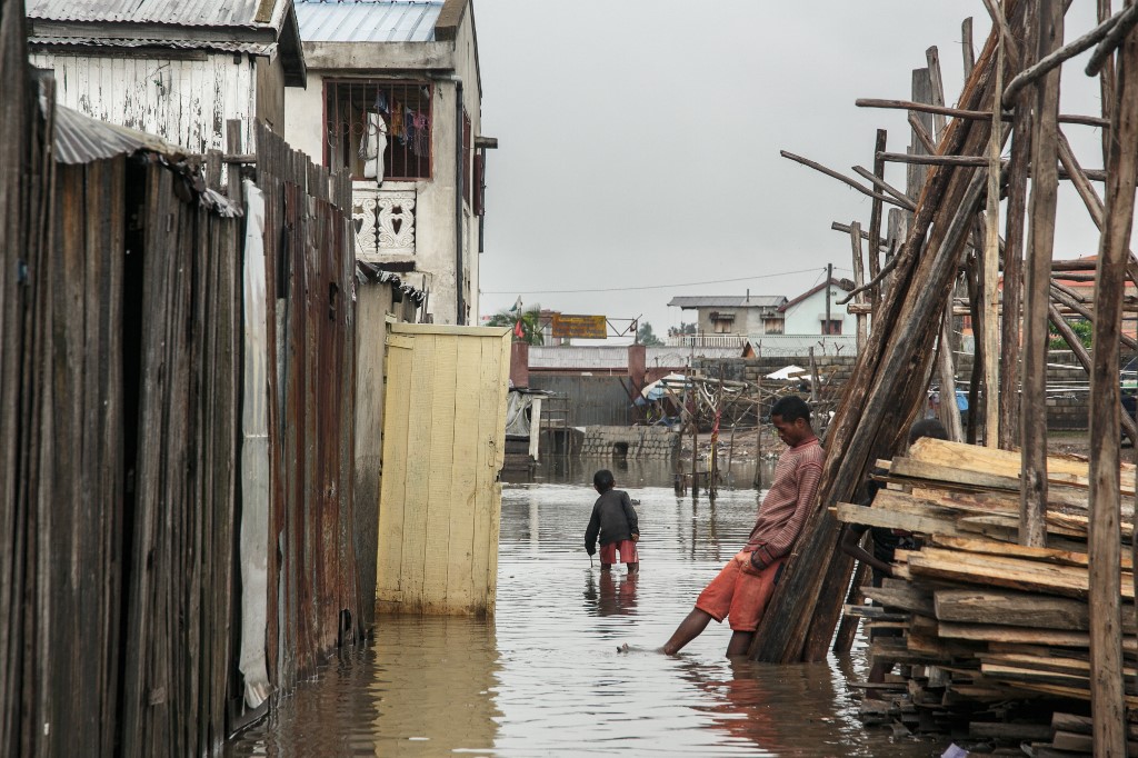 Garotos com expressões tristes em meio à área inundada de Antananarivo, capital de Madagascar