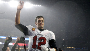 Tom Brady acena com o braço direito estendido em estádio lotado