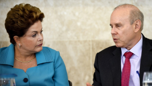 Sentados, Dilma Rousseff (de vestido lilás) e seu ministro Guido Mantega (de terno e gravata) conversam durante reunião do Conselho de Desenvolvimento Econômico e Social no Palácio do Planalto, em Brasília, em 5 de junho de 2014