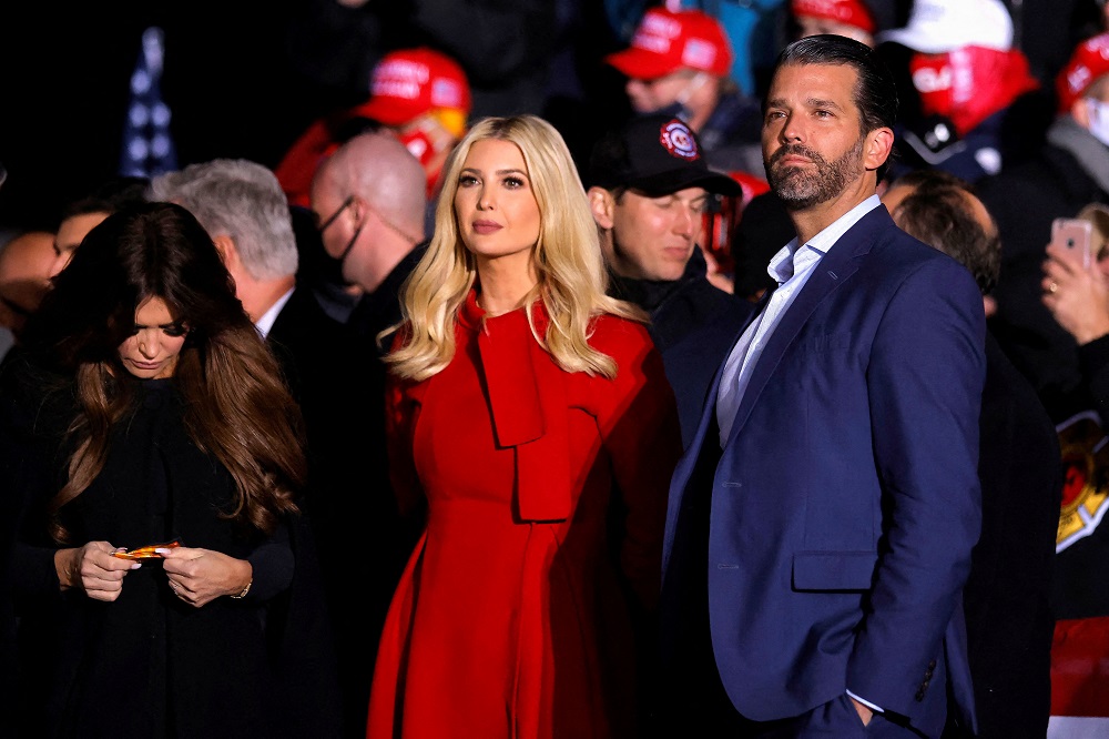 Ivanka Trump (mulher loira em vestido vermelho), ao lado do irmão, Donald Trump Jr. (homem branco em terno azul)
