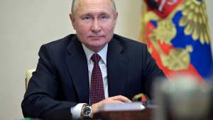 Vladimir Putin de terno e gravata, com bandeira ao fundo