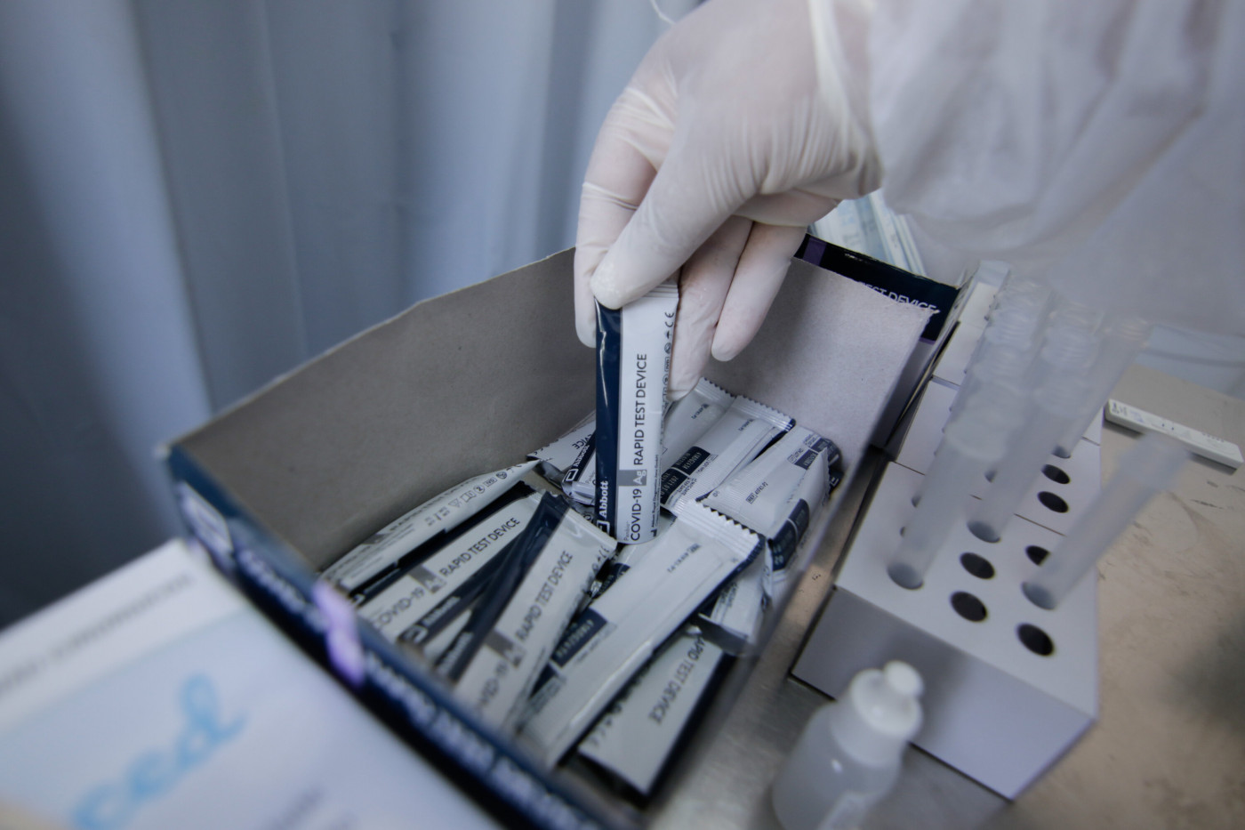 Mão de enfermaria pegando testes de Covid-19 em uma caixa