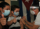 Crianças ao lado da mãe recebendo vacina contra a Covid-19 por uma enfermeira