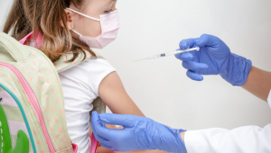 Criança com mochila recebe dose de vacina