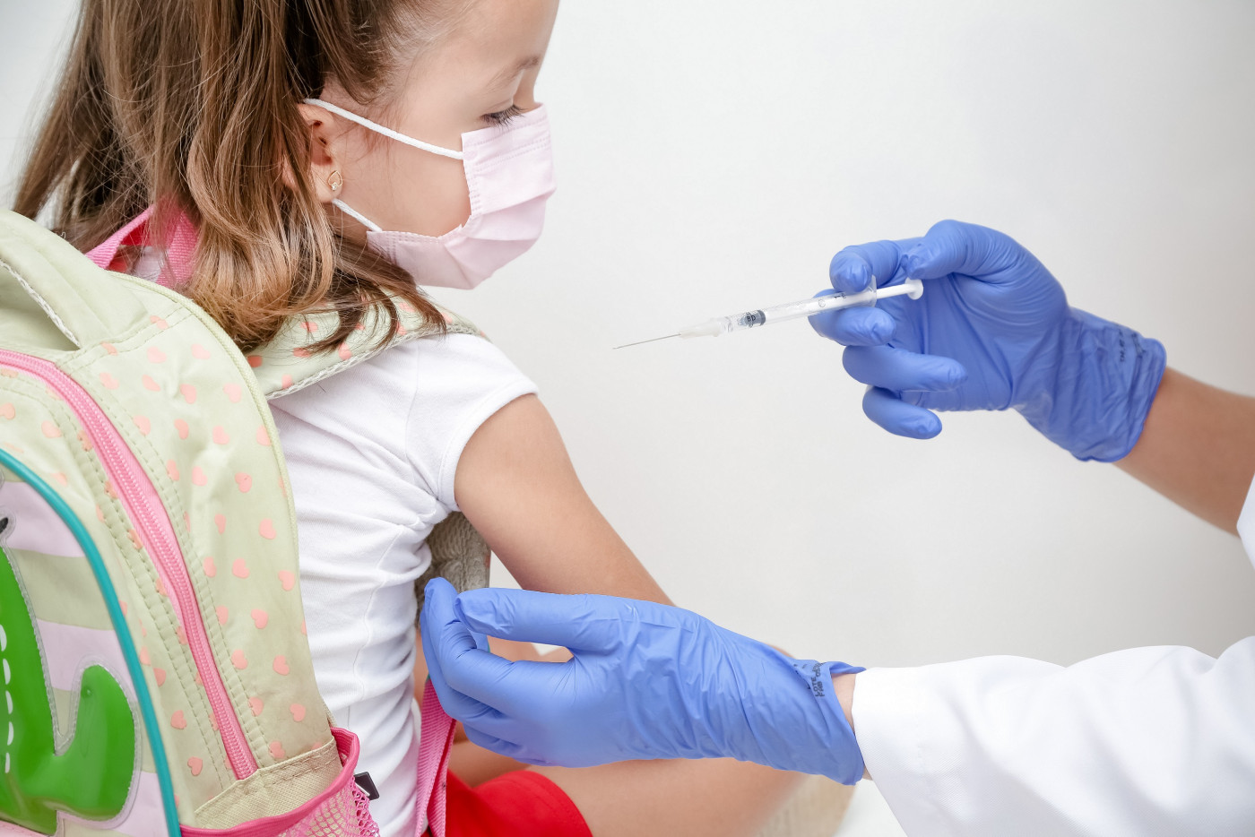 Criança com mochila recebe dose de vacina