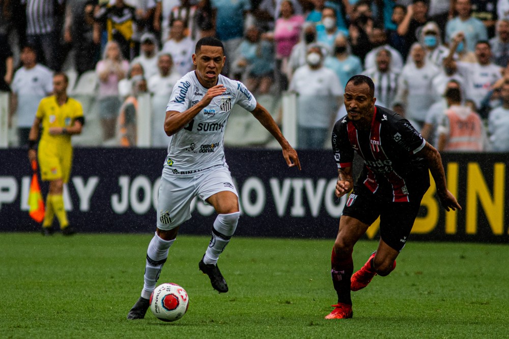 Na Vila Belmiro, o santista Marcos Guilherme parte com a bola dominada seguido de perto por jogador do Botafogo