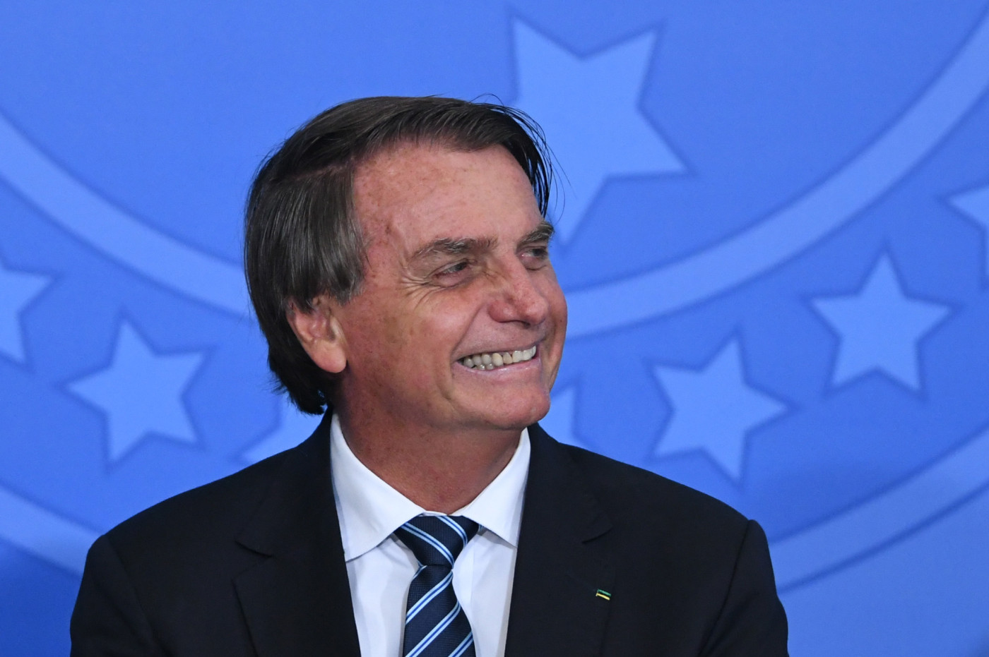 O presidente Jair Bolsonaro olhando para o lado e sorrindo