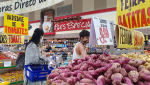 Uma mulher e seu filho pré-adolescente circulam de máscara pelo corredor dos tubérculos em supermercado