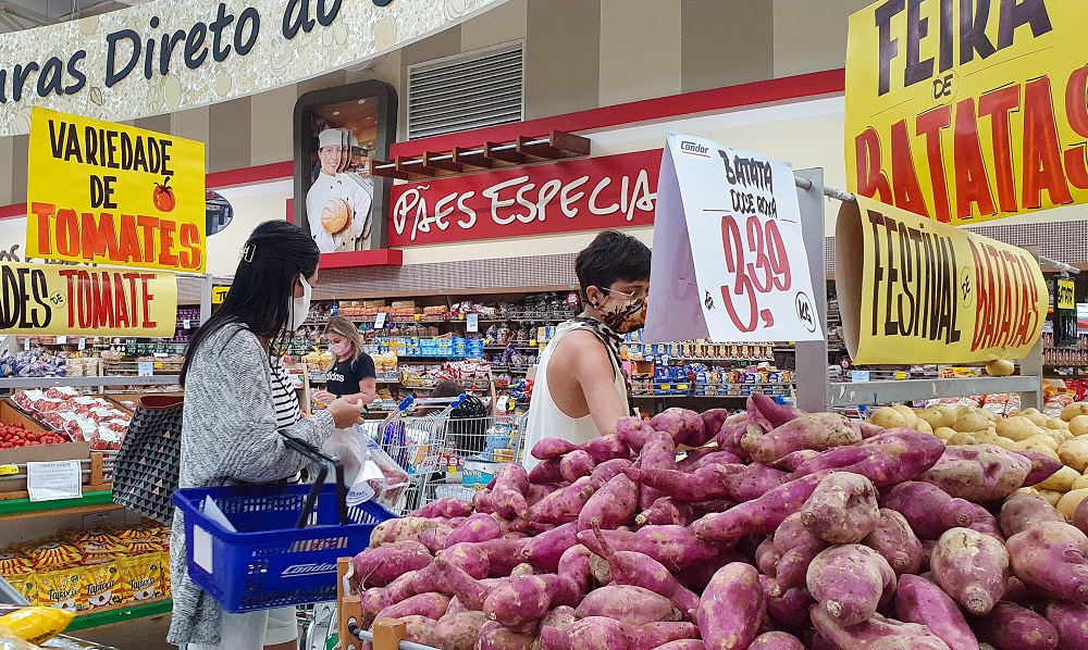 Uma mulher e seu filho pré-adolescente circulam de máscara pelo corredor dos tubérculos em supermercado