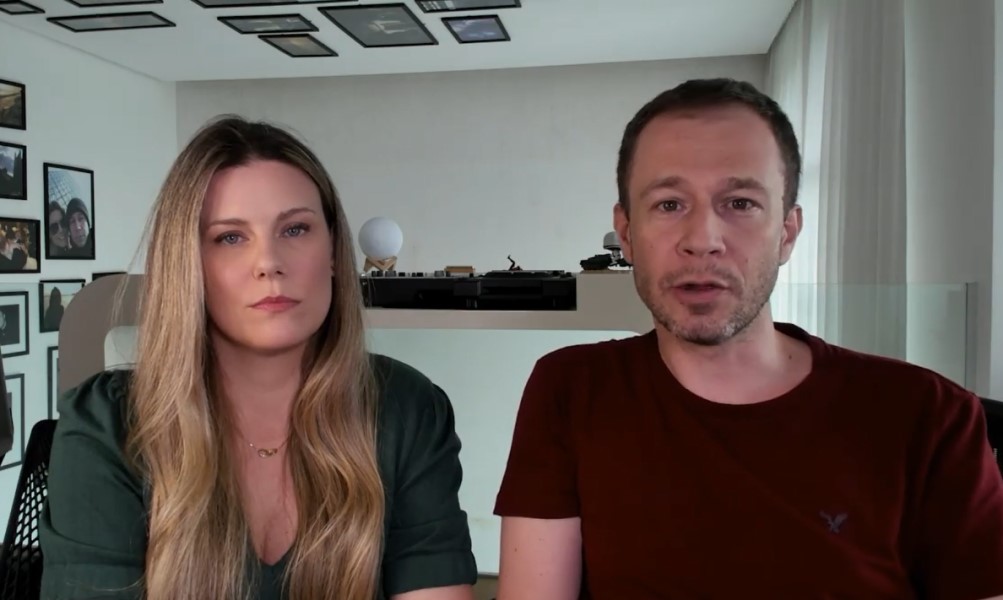 Sentado em frente a uma câmera, o casal Diana Garbin e Tiago Leifert grava vídeo em um cômodo da casa