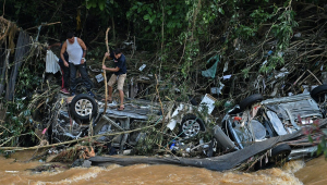 Pessoas tentam resgatar itens de carros destruídos por uma enchente em Petrópolis