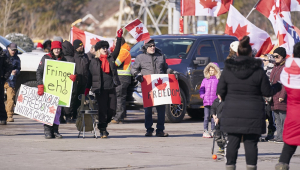 Manifestantes canadenses contra o passaporte da vacina seguram cartazes enquanto bloqueiam a fronteira com os Estados Unidos