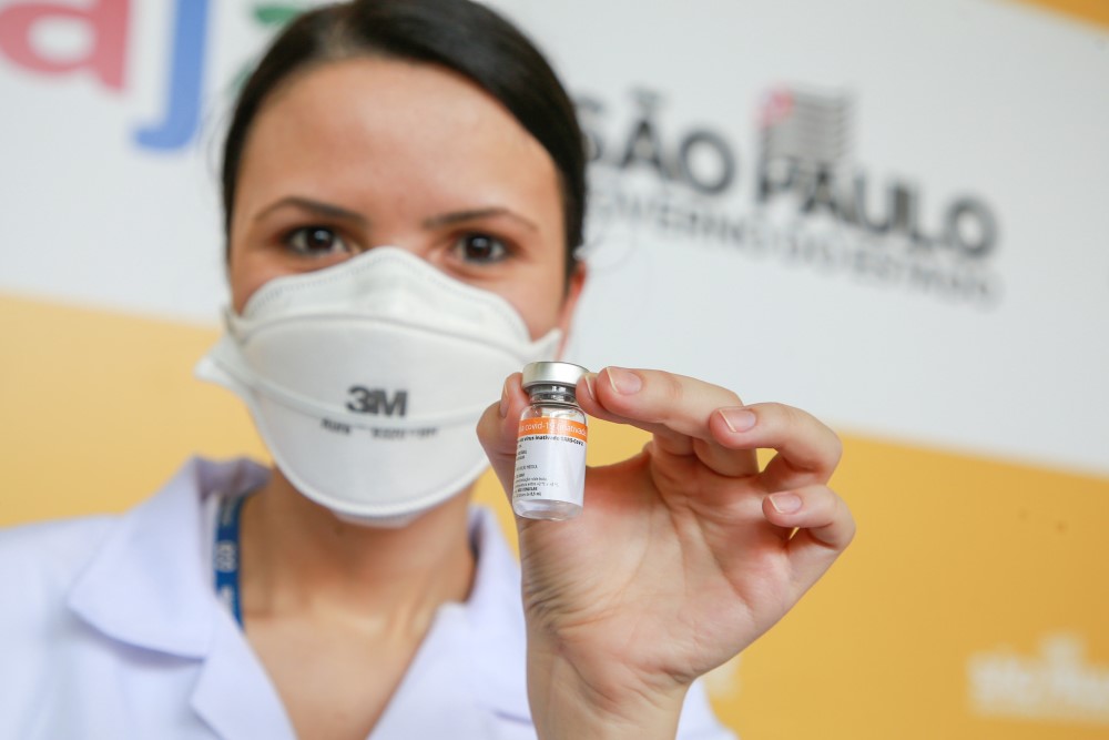 Enfermeira de máscara PFF3 mostra frasco de vacina