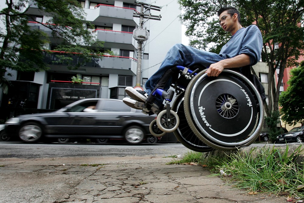 Cadeirante se equilibra na cadeira de rodas em calçada de São Paulo