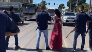 Mulher atravessa a rua com homens armados