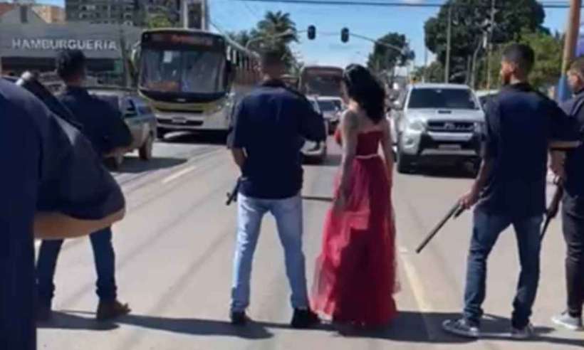 Mulher atravessa a rua com homens armados