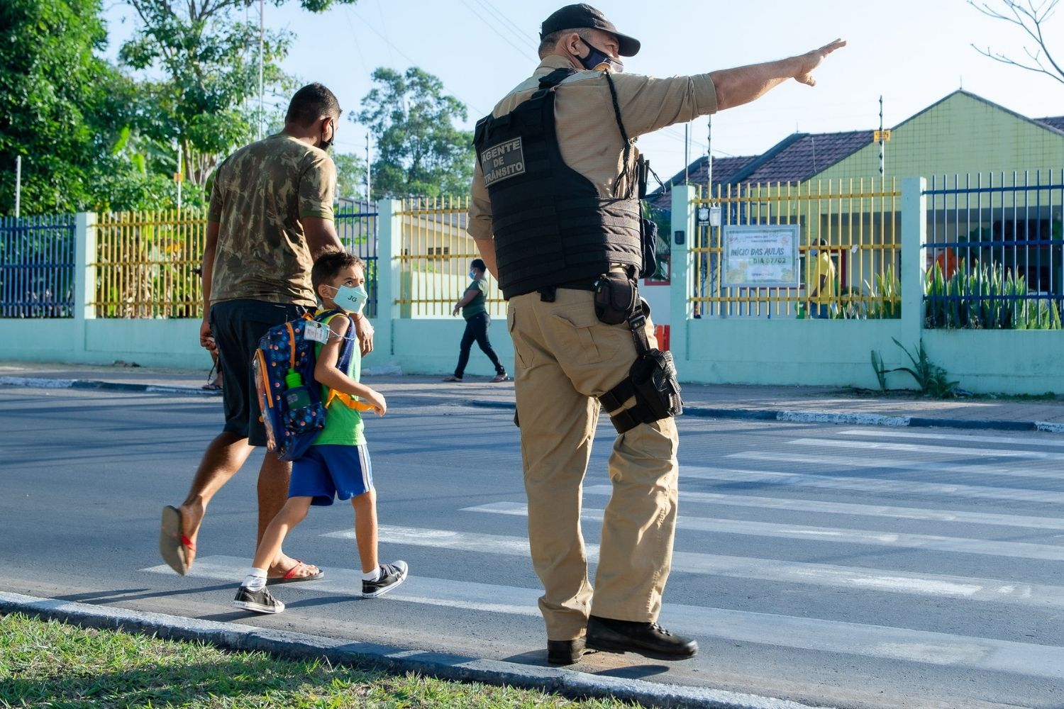 Policial acena para que pai atravesse a rua com seu filho