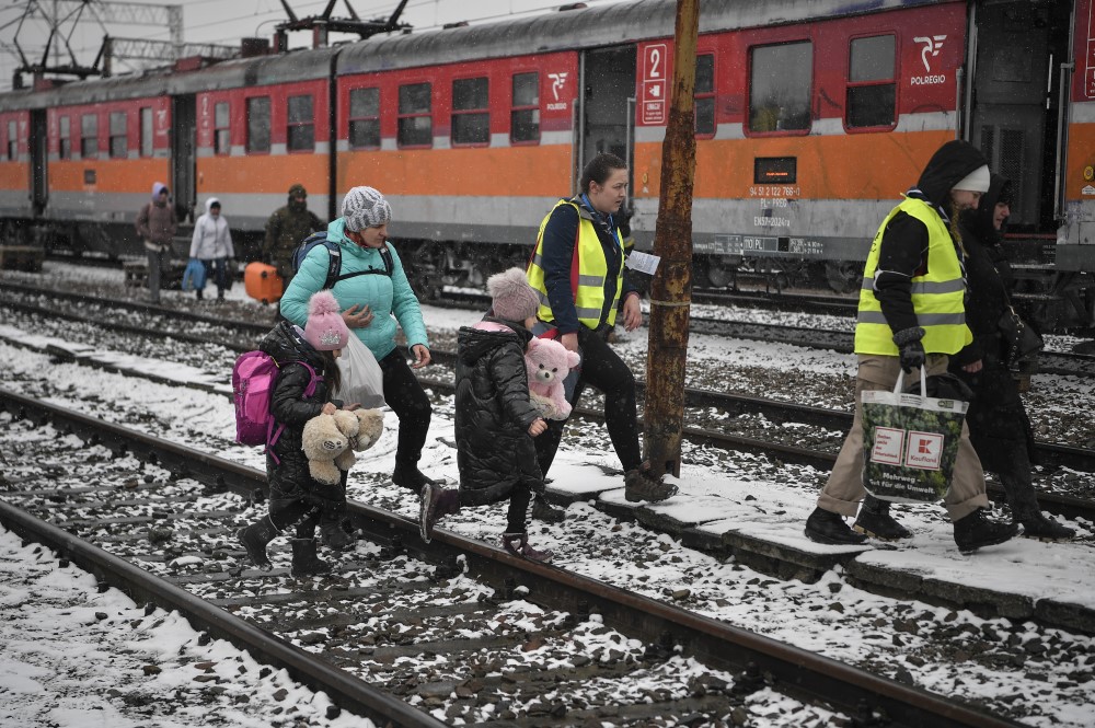 Refugiados recém-chegados da Ucrânia são assistidos por voluntários para embarcar em um trem