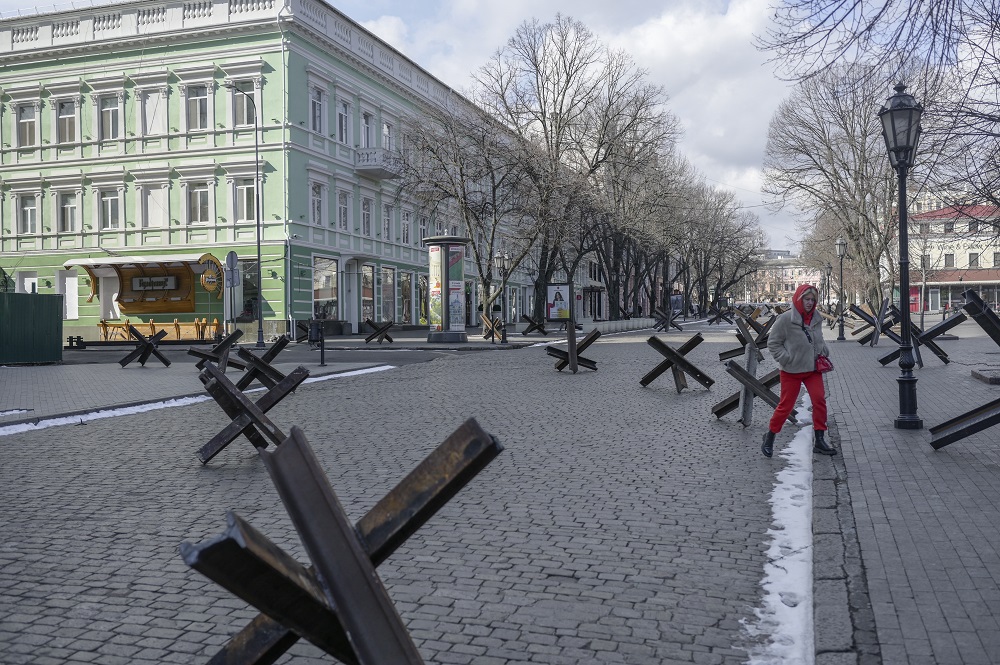Um morador atravessa uma rua vazia ao lado de obstáculos antitanque em Odessa