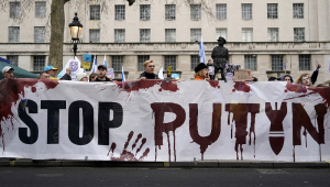 Com uma grande faixa escrita "Parem Putin" em inglês, pessoas participam de uma manifestação em apoio à Ucrânia