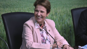 Sentada em uma cadeira, ministra Teresa Cristina sorri