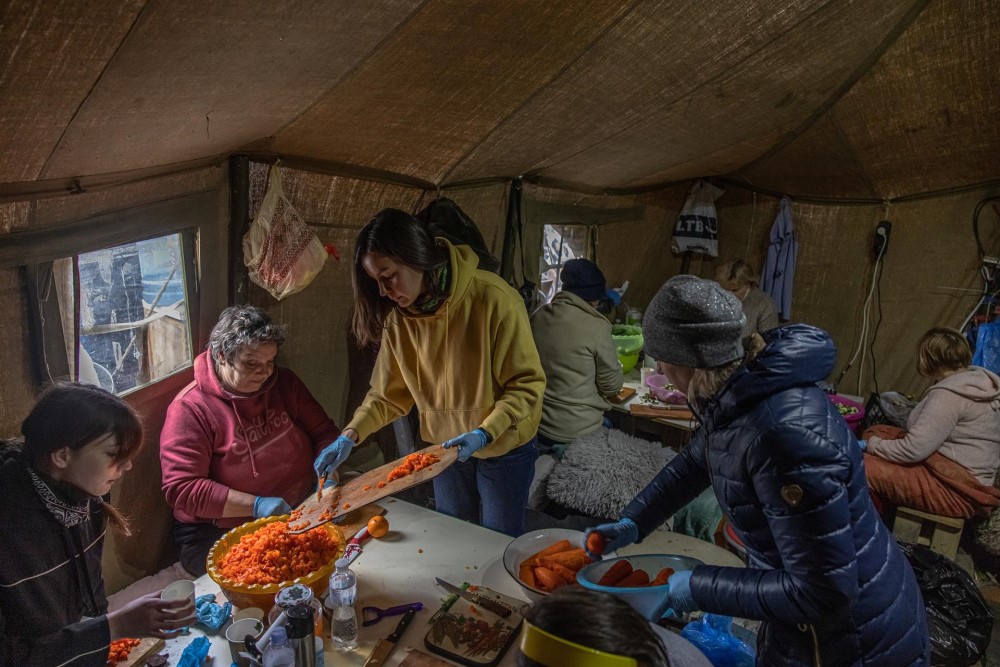 Mulheres ucranianas cozinham dentro de uma barraca em um acampamento improvisado ao lado de um posto de controle, em Kiev